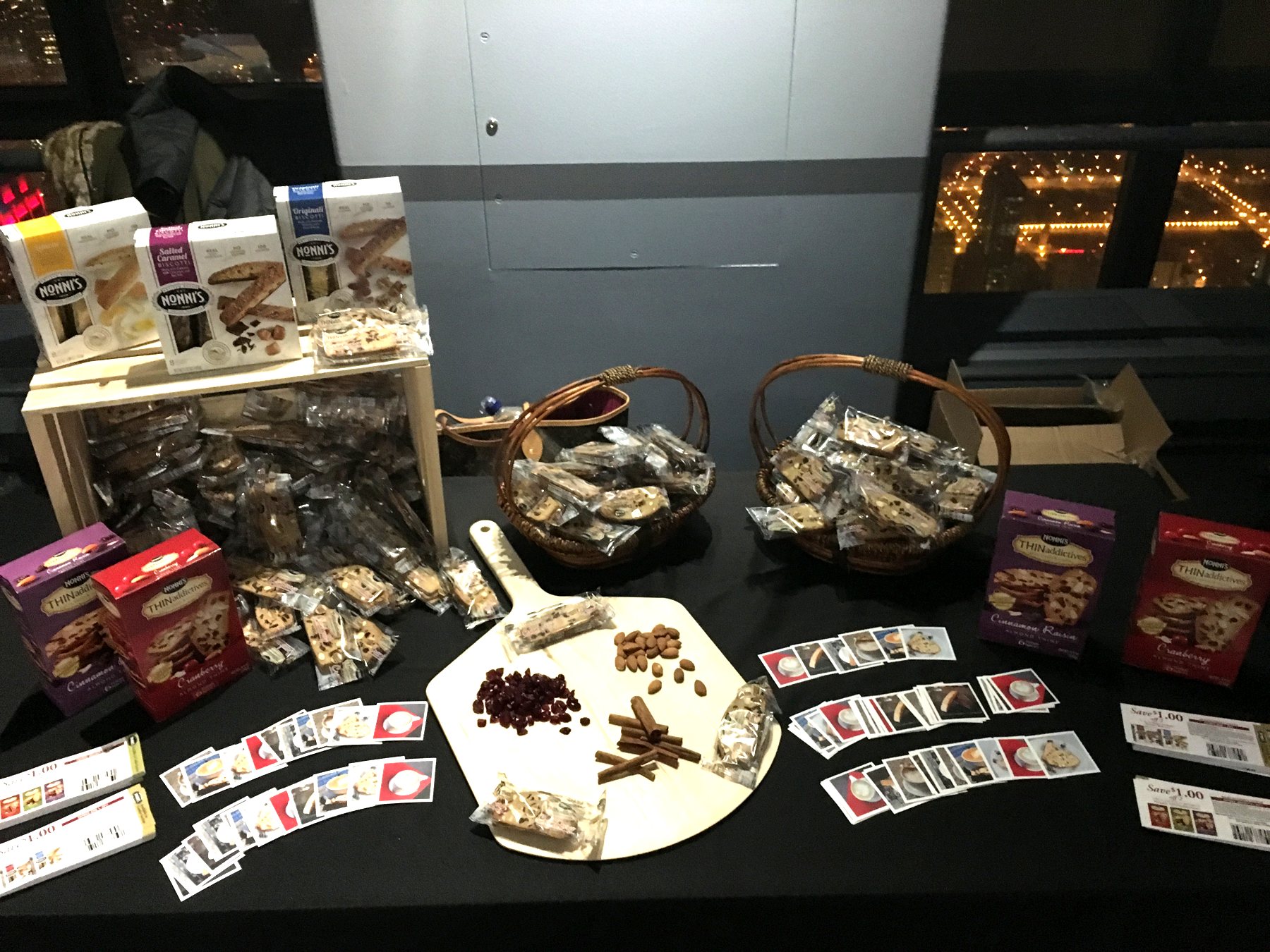 Nonni's tasting table with biscotti, recipe cards and city lights behind it