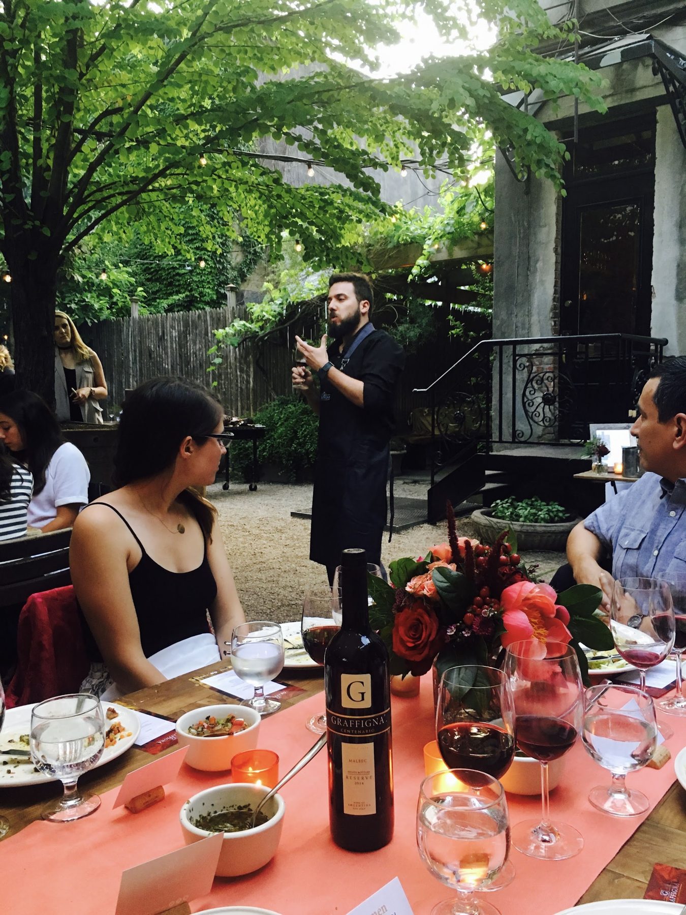 A speaker addresses diners; a Graffigna wine bottle is in the foreground