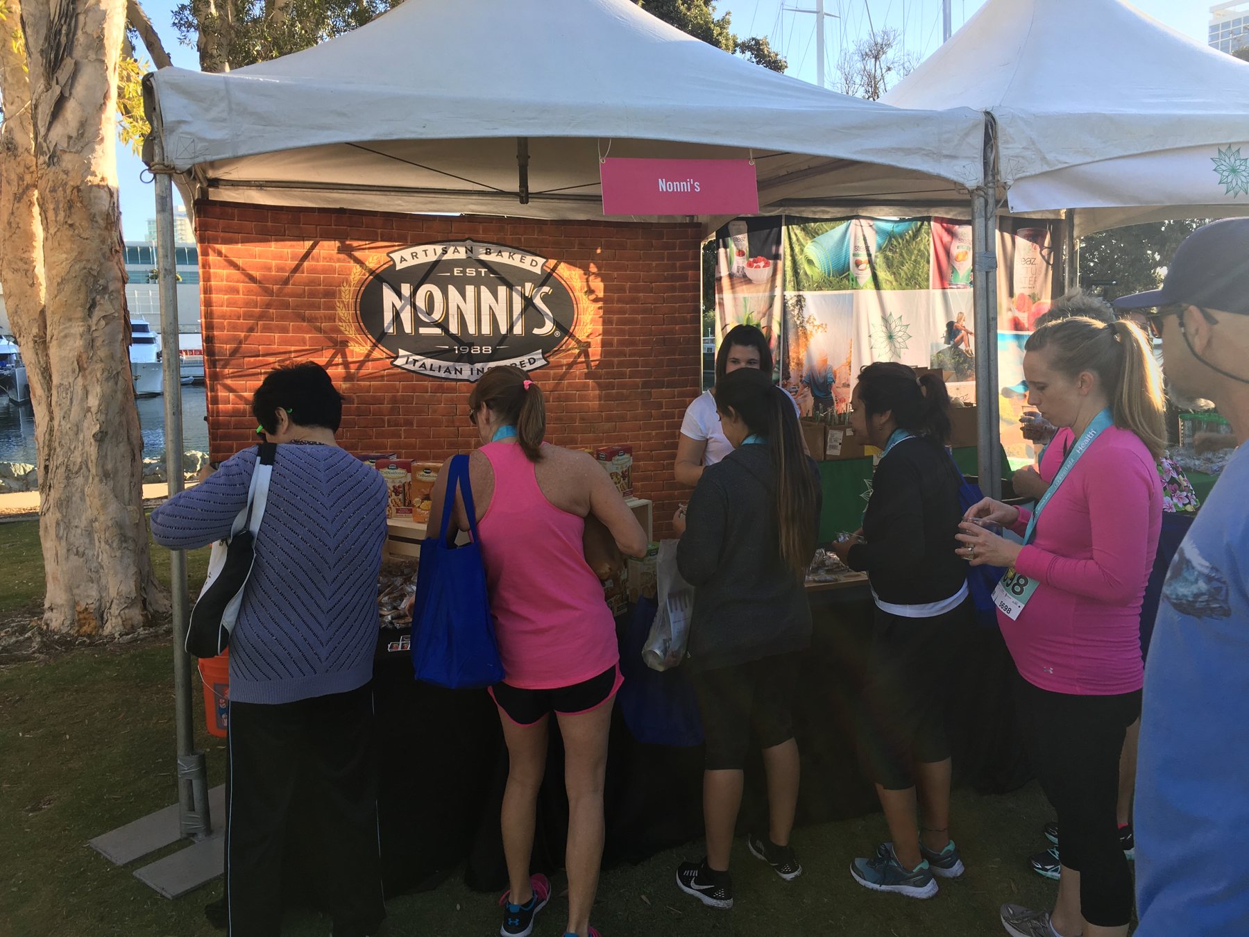 Runners with race medals sampling at the Nonni's tent by the harbor
