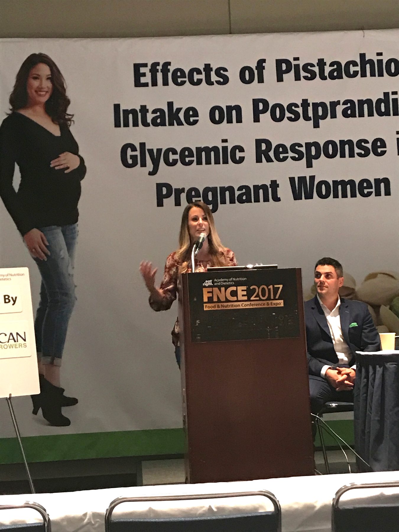 A speaker at a podium before a banner about pistachio intake research at FNCE 2017