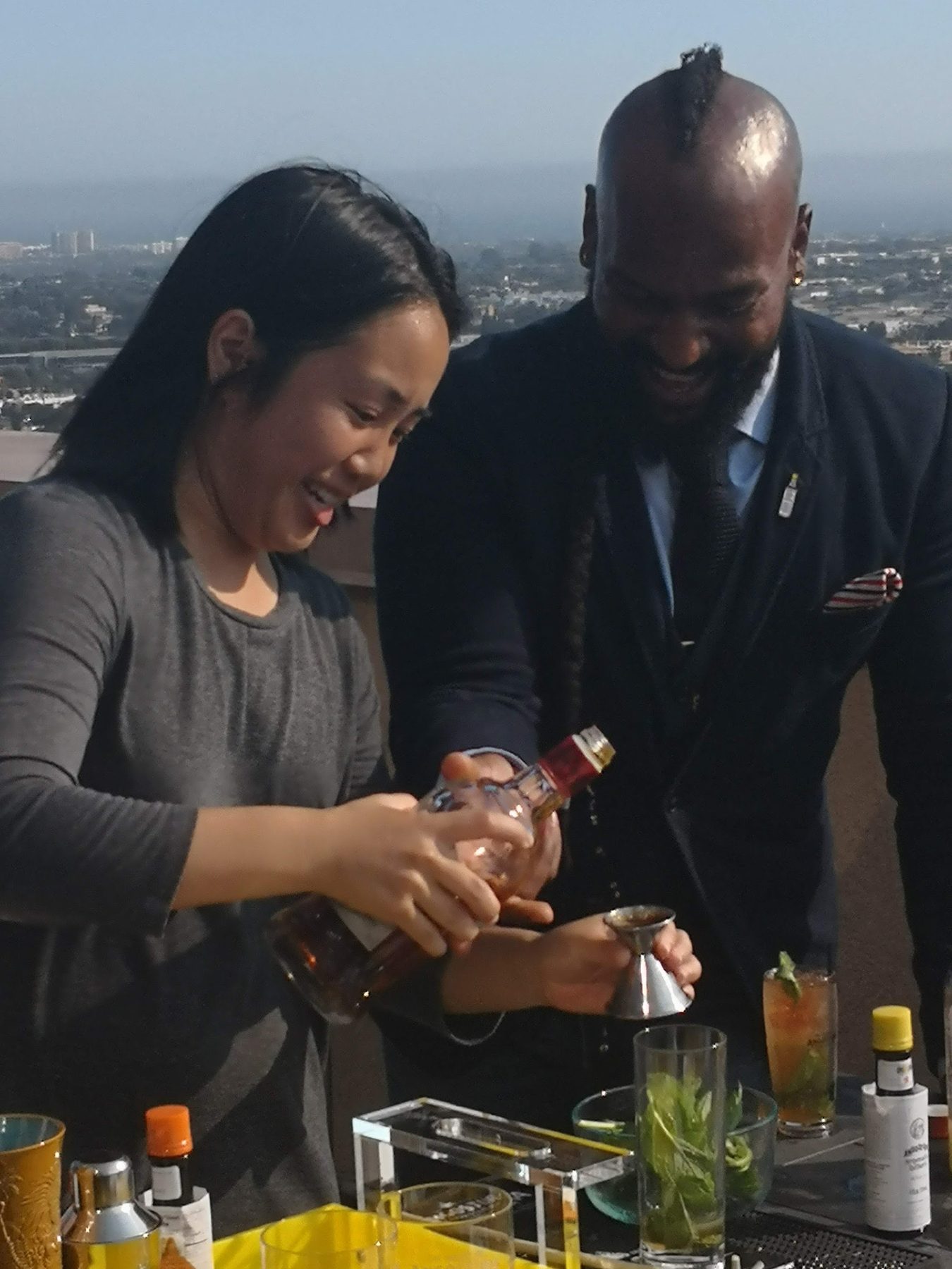 A bartender and a guest mixing cocktails at a rooftop bar