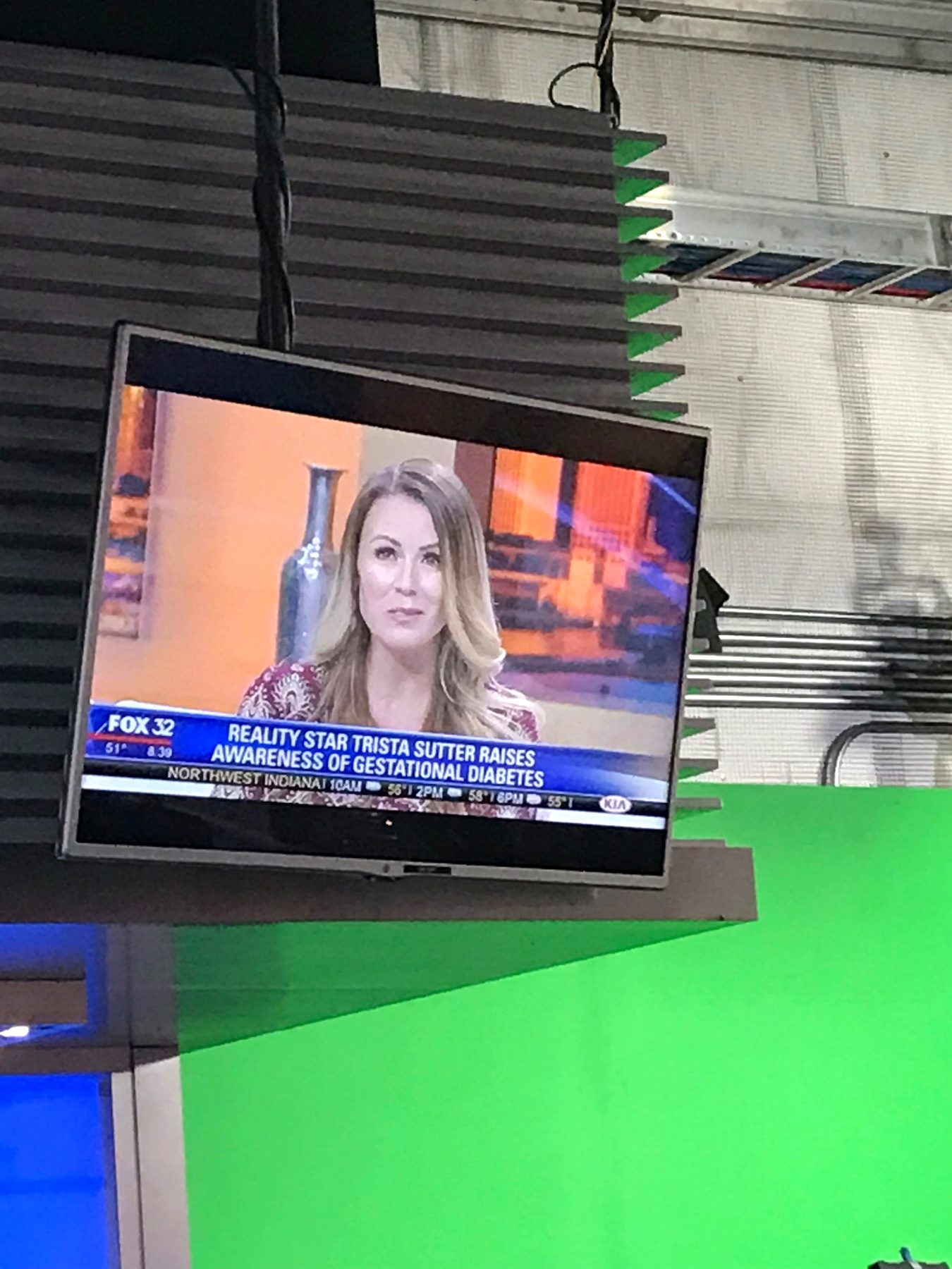 A TV monitor showing a Fox 32 interview with Trista Sutter in a studio