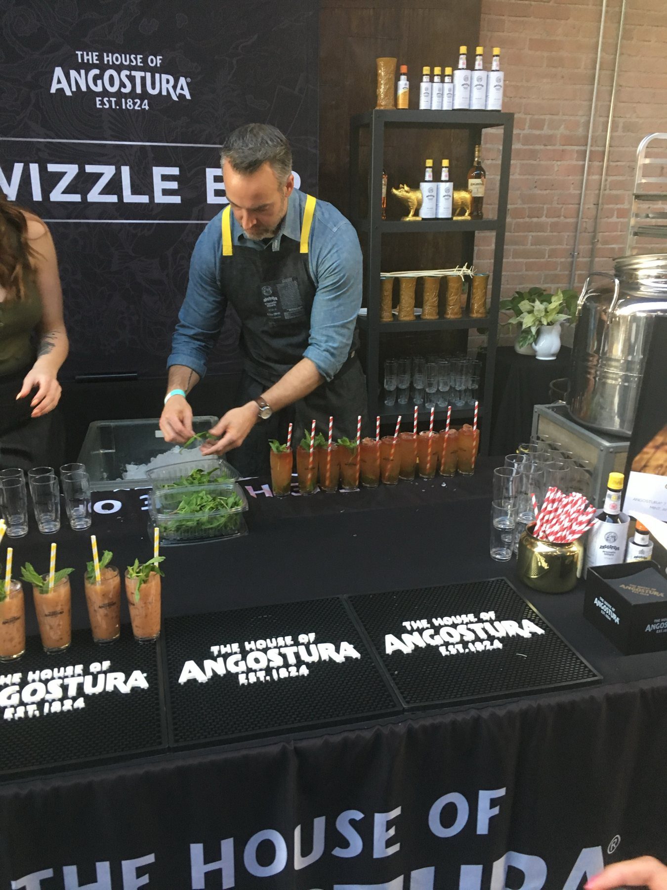 A bartender garnishing a row of swizzle cocktails at a House of Angostura branded bar