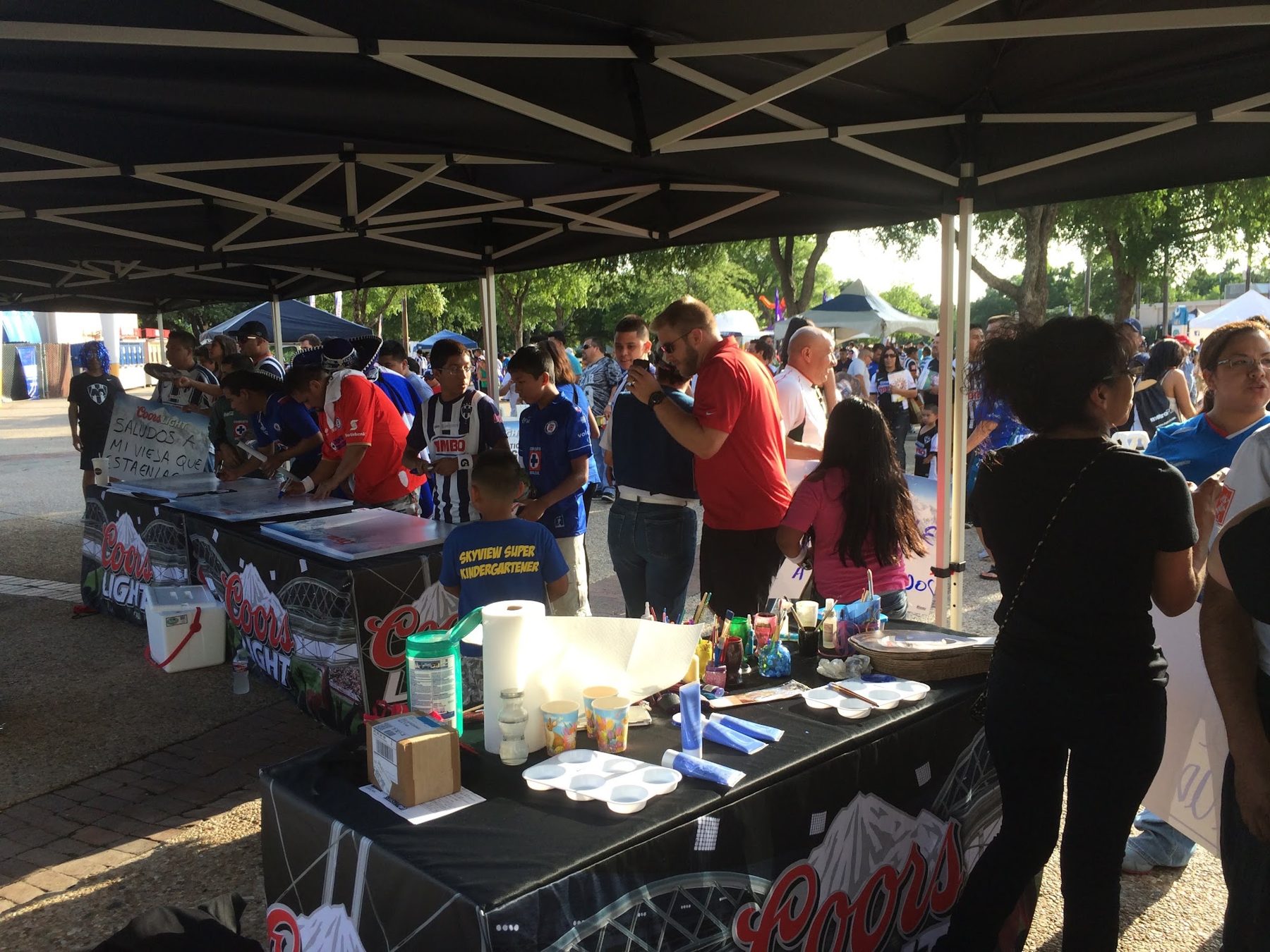 Soccer fans in jerseys gathered at a Coors-branded tent