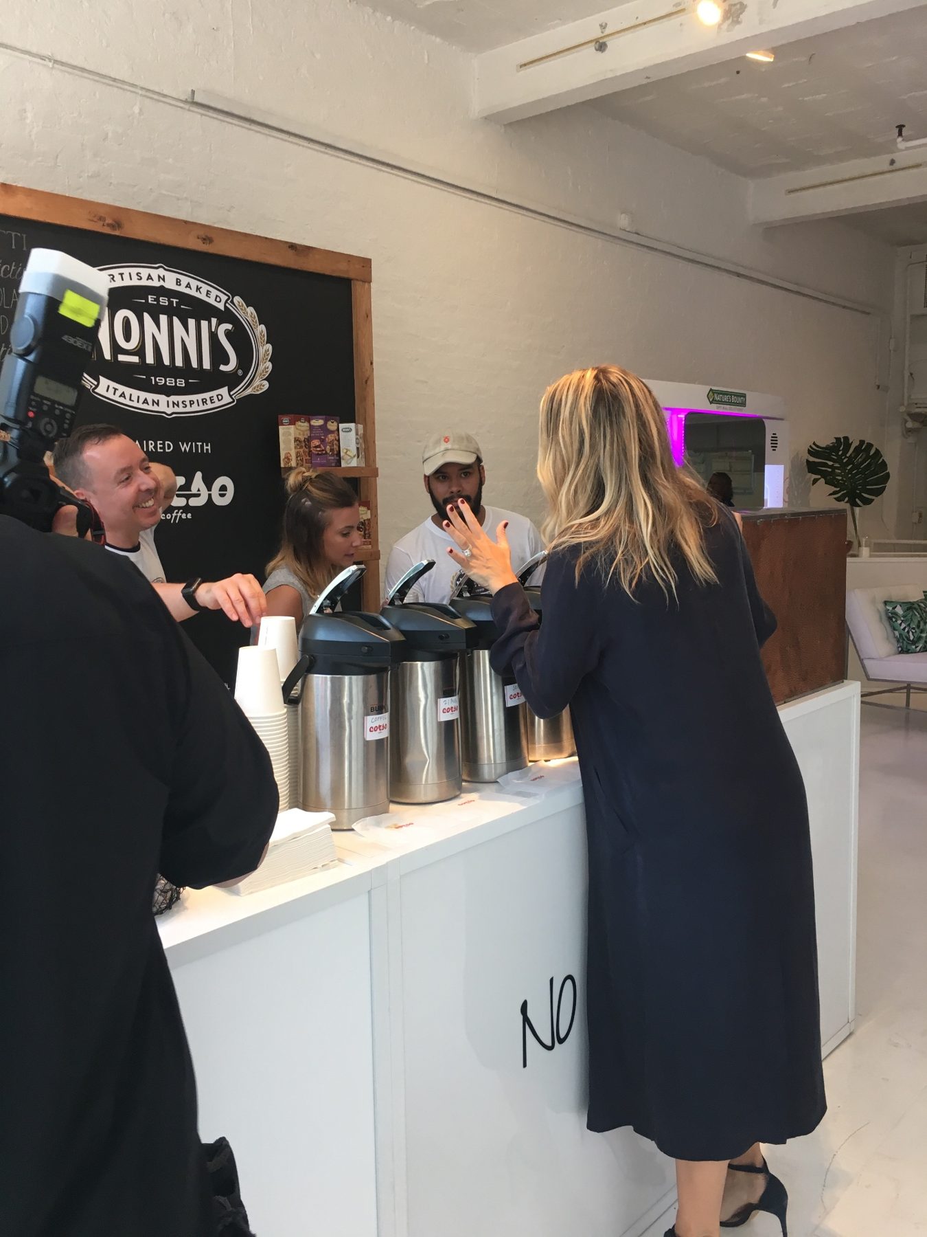 A guest in a navy dress speaking with the Nonni's café team while a photographer captures the visit