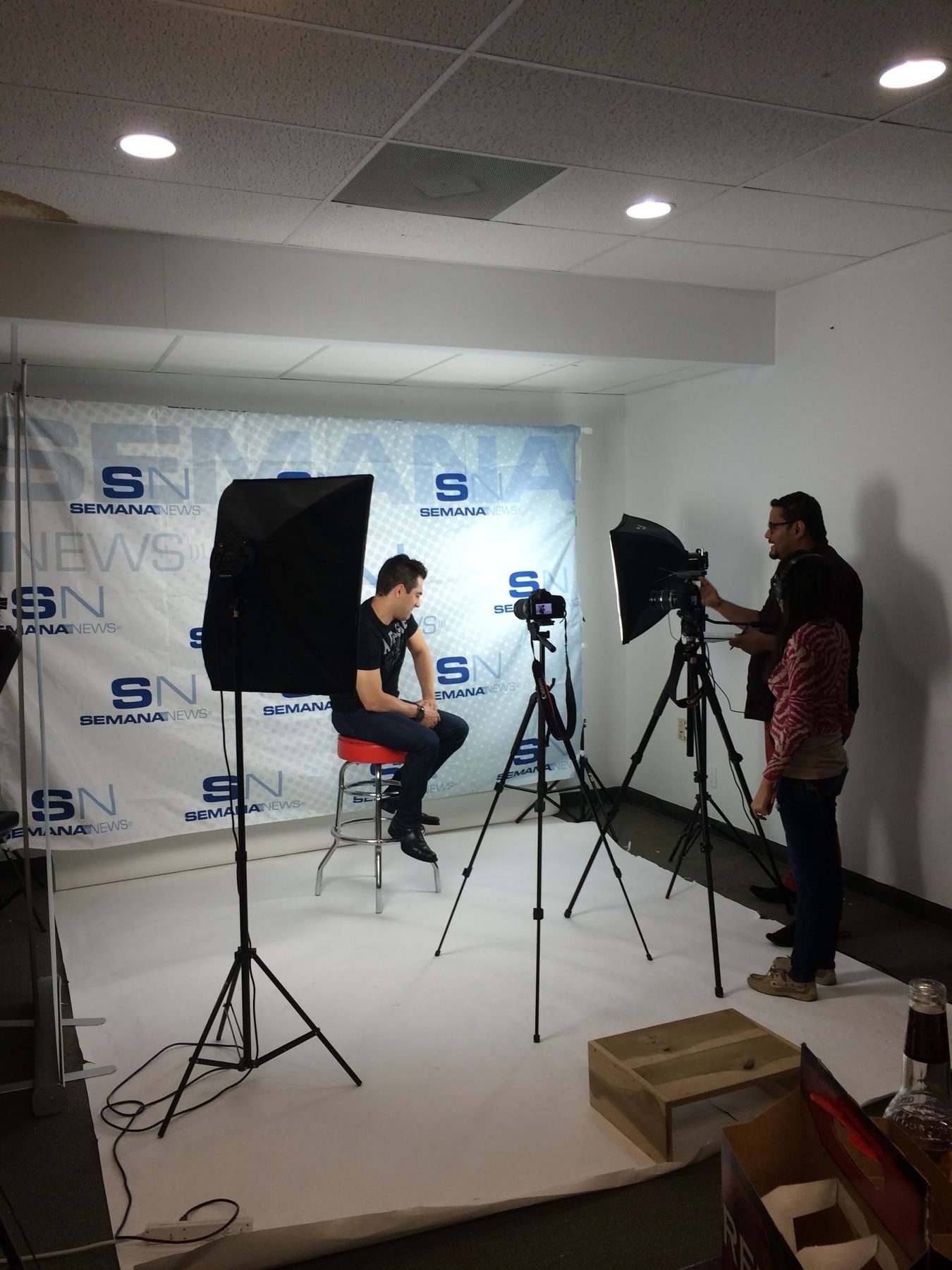 A spokesperson being filmed in a studio in front of a branded backdrop